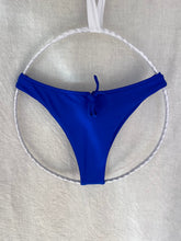 Load image into Gallery viewer, Blue surf bikini bottom on a white circular stand against a light gray background